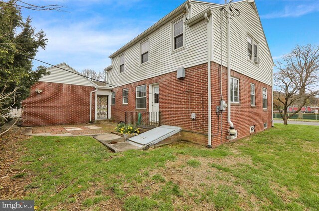 back of property with a yard and brick siding