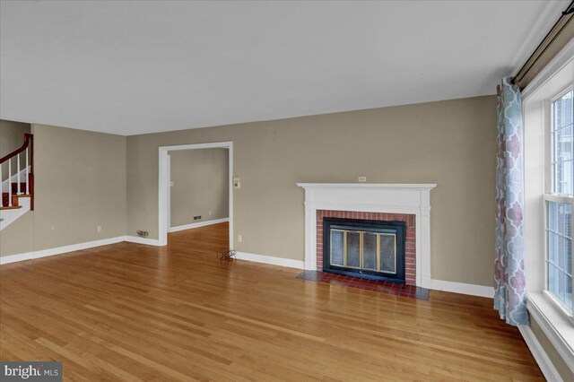 unfurnished living room featuring wood finished floors, a fireplace, and baseboards