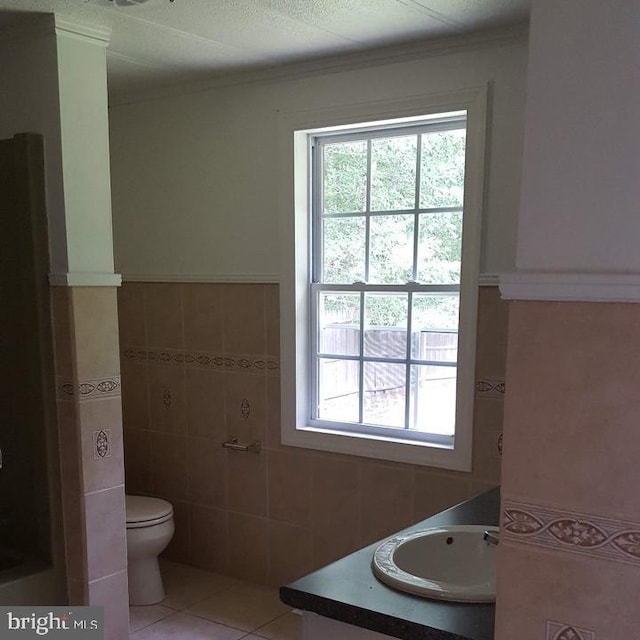 bathroom with crown molding, vanity, tile patterned flooring, toilet, and tile walls