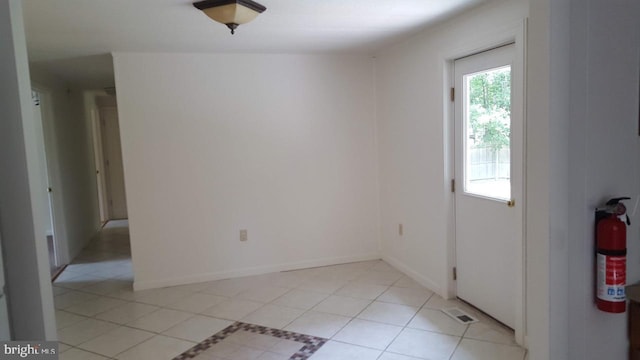 spare room featuring light tile patterned floors, visible vents, and baseboards