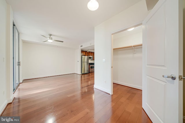 unfurnished bedroom with light wood finished floors, visible vents, baseboards, freestanding refrigerator, and a spacious closet