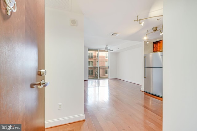 interior space with visible vents, a ceiling fan, light wood finished floors, and baseboards