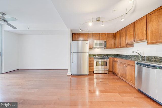 kitchen featuring light wood finished floors, a sink, brown cabinets, and stainless steel appliances