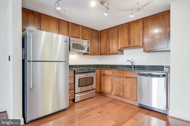 kitchen with light wood-style floors, appliances with stainless steel finishes, and brown cabinets