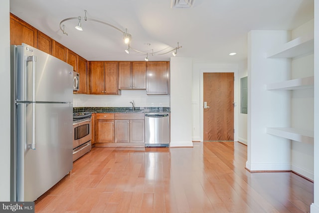 kitchen featuring a sink, open shelves, brown cabinetry, light wood-style flooring, and appliances with stainless steel finishes