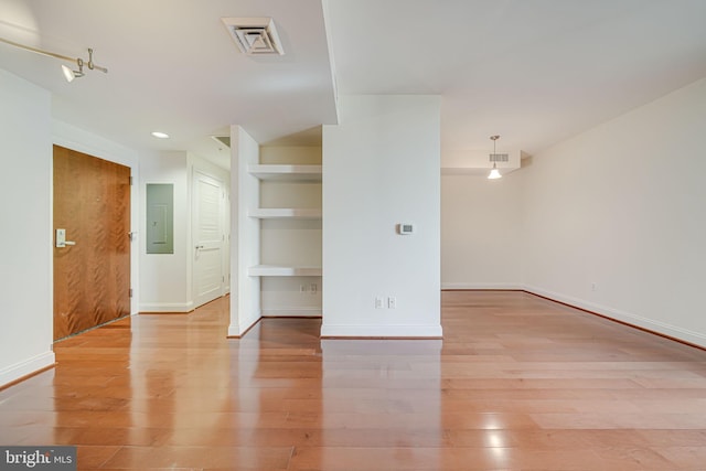 empty room featuring baseboards, visible vents, wood finished floors, and electric panel