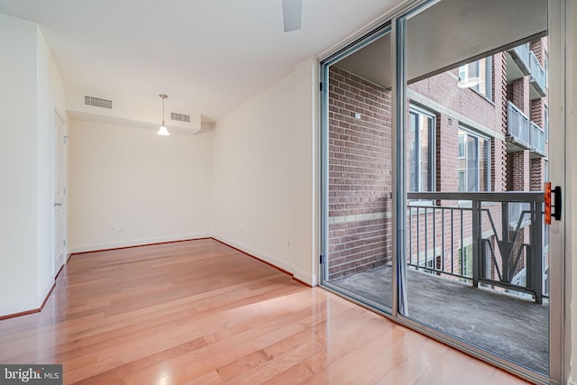 empty room featuring wood finished floors, visible vents, and baseboards
