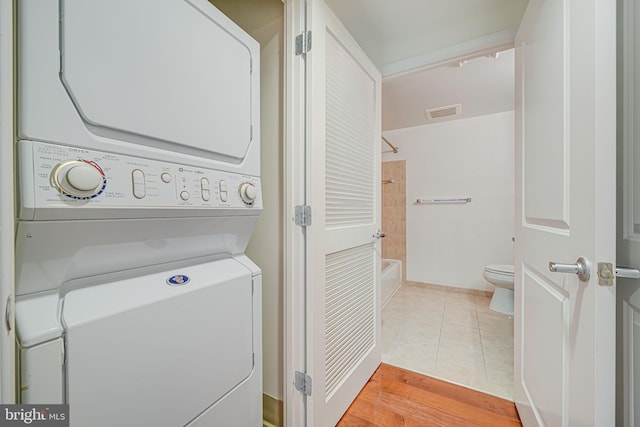 laundry area with stacked washer and dryer, visible vents, light tile patterned floors, and laundry area