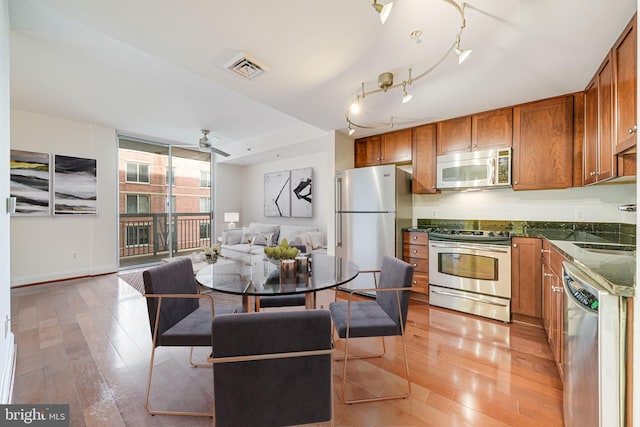 kitchen featuring brown cabinetry, appliances with stainless steel finishes, light wood-type flooring, baseboards, and visible vents