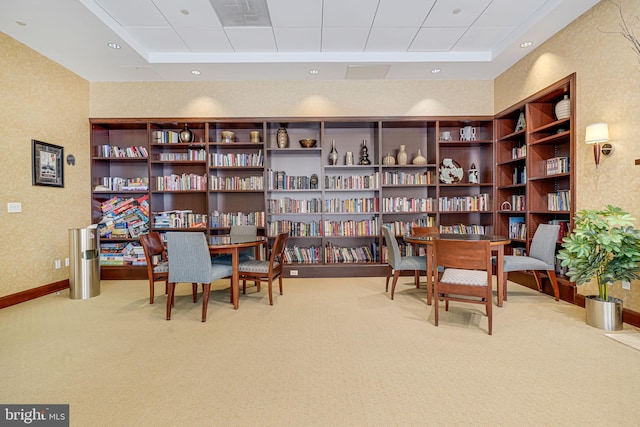 interior space with a paneled ceiling, wall of books, visible vents, baseboards, and carpet floors