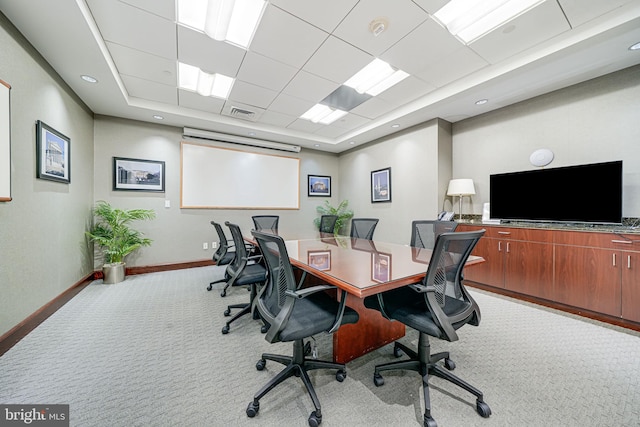 carpeted office space with visible vents, a raised ceiling, and baseboards