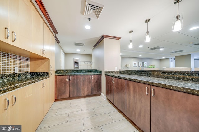 kitchen featuring dark stone countertops, visible vents, tasteful backsplash, and hanging light fixtures
