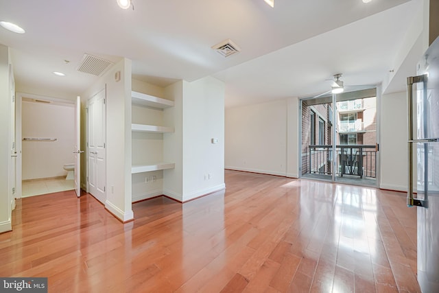 spare room with a ceiling fan, visible vents, light wood-style flooring, and baseboards
