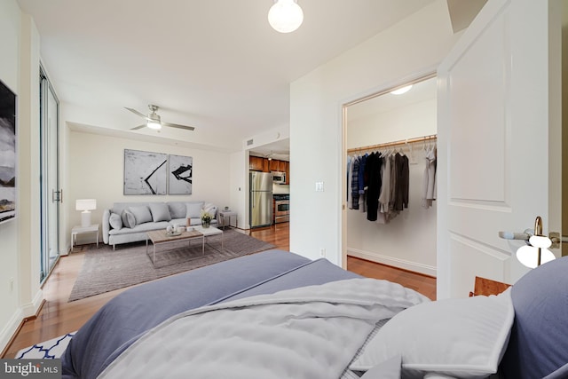 bedroom featuring a closet, a walk in closet, visible vents, freestanding refrigerator, and wood finished floors