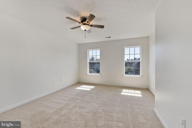 carpeted spare room with a textured ceiling, baseboards, a ceiling fan, and visible vents