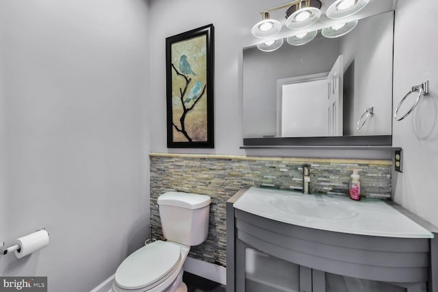 bathroom with toilet, vanity, and a wainscoted wall