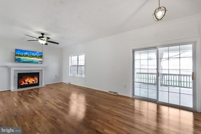 unfurnished living room with a fireplace with flush hearth, a ceiling fan, visible vents, wood finished floors, and baseboards