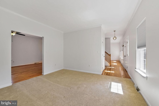 unfurnished living room featuring ornamental molding, visible vents, carpet, and stairs
