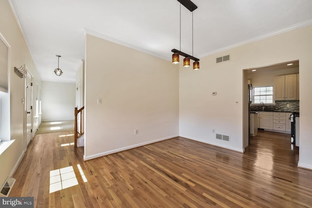 unfurnished dining area with visible vents, ornamental molding, and wood finished floors