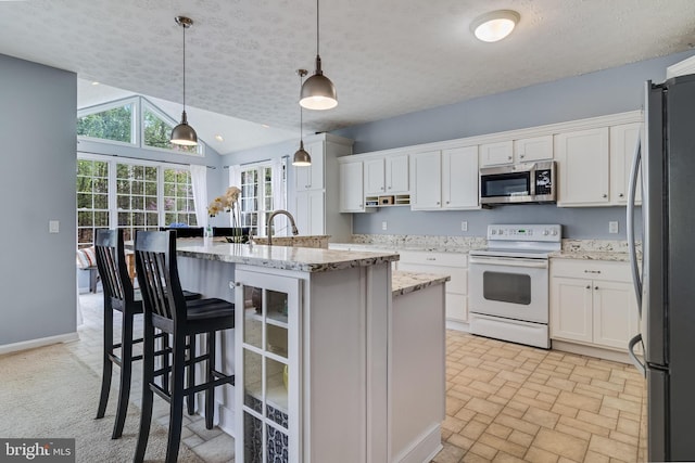 kitchen with appliances with stainless steel finishes, wine cooler, white cabinetry, light stone countertops, and lofted ceiling