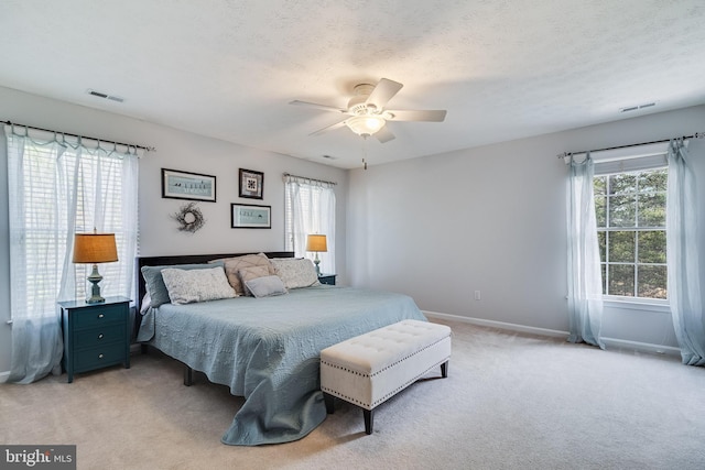 bedroom featuring light carpet, visible vents, and multiple windows