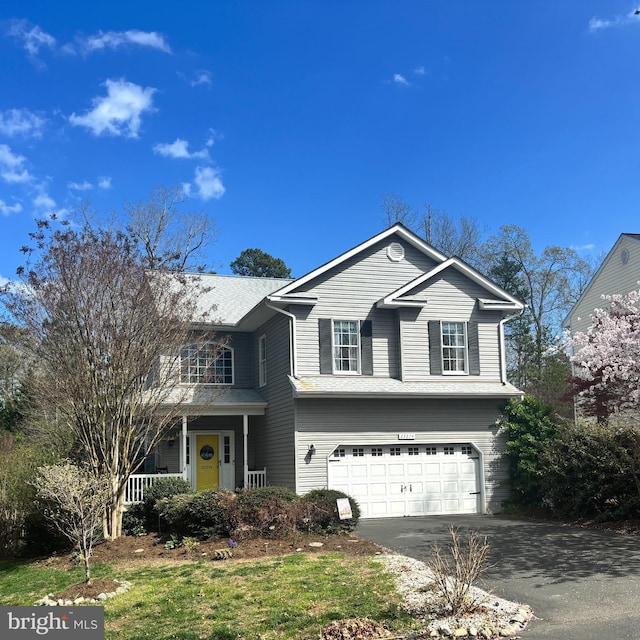 traditional-style home featuring an attached garage, aphalt driveway, and covered porch