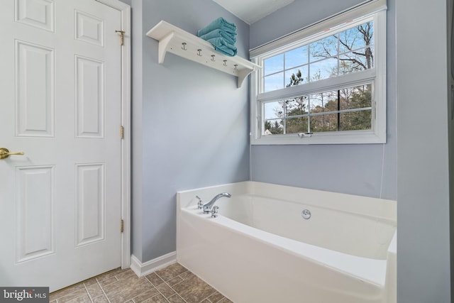 bathroom featuring a garden tub and baseboards