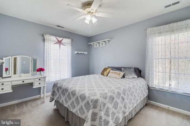 carpeted bedroom with visible vents, baseboards, and a ceiling fan