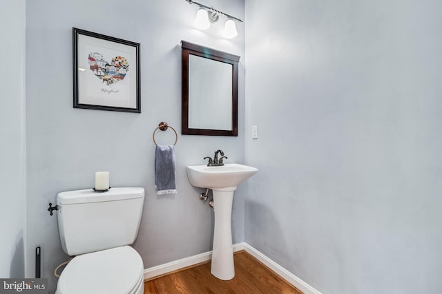 half bath featuring toilet, baseboards, and wood finished floors