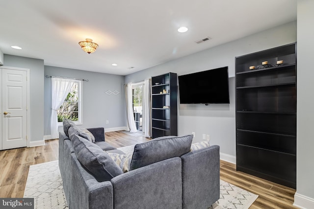 living room with recessed lighting, visible vents, baseboards, and wood finished floors