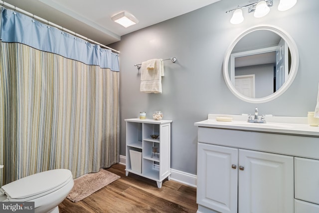 bathroom with toilet, baseboards, vanity, and wood finished floors