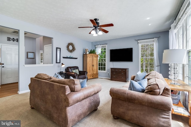 living area with light colored carpet, ceiling fan, and baseboards