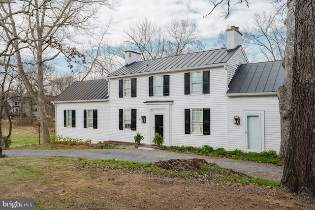 colonial home with metal roof, a standing seam roof, and a chimney