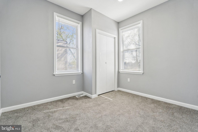 unfurnished bedroom with carpet floors, baseboards, a closet, and visible vents