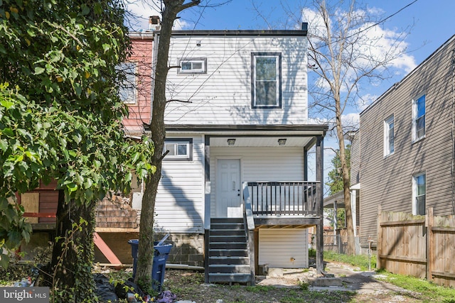 rear view of property featuring stairway and fence