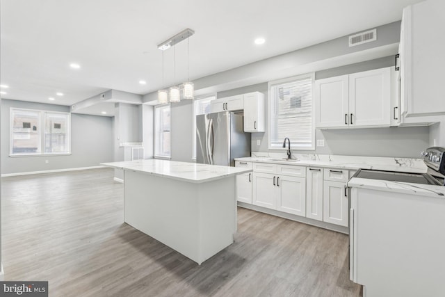kitchen with light wood-style flooring, freestanding refrigerator, a sink, and a kitchen island