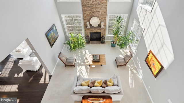 living room featuring baseboards, wood finished floors, a towering ceiling, and a fireplace