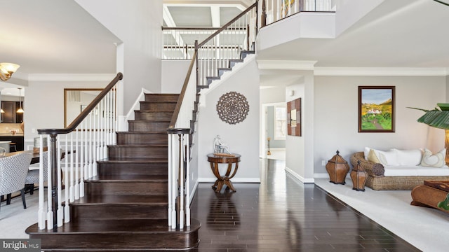 staircase with baseboards, crown molding, wood finished floors, and a high ceiling