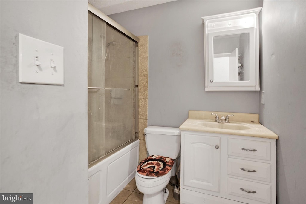 bathroom featuring tile patterned floors, bath / shower combo with glass door, toilet, and vanity