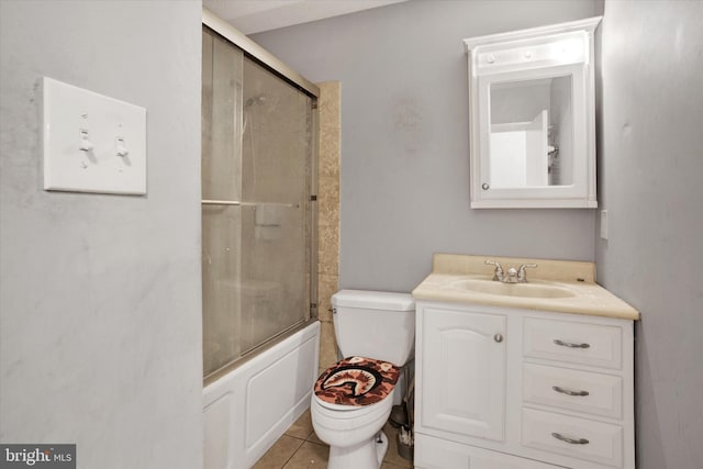 bathroom featuring tile patterned floors, bath / shower combo with glass door, toilet, and vanity