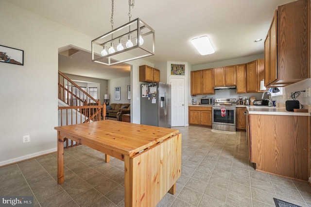 720 Birch Tree Ln, Smyrna, DE 19977 - kitchen featuring appliances with stainless steel finishes, light countertops, brown cabinetry, a sink, and hanging light fixtures