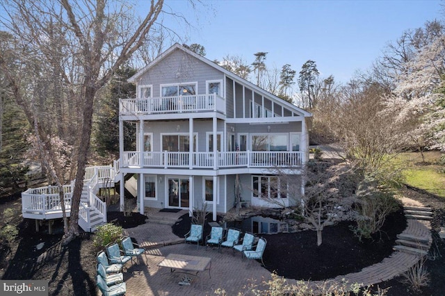 rear view of house featuring a wooden deck, a balcony, stairway, and a patio area