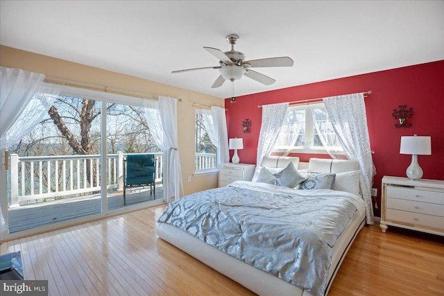 bedroom with hardwood / wood-style floors, access to outside, multiple windows, and a ceiling fan
