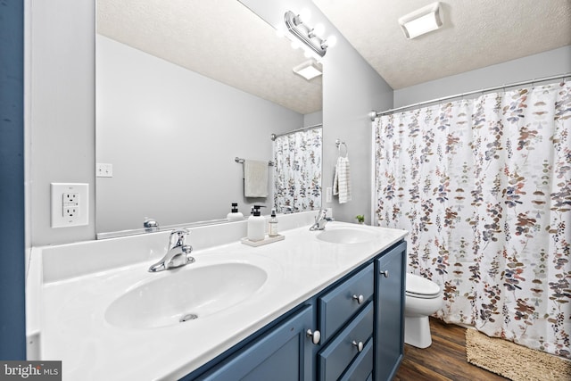 full bathroom with toilet, a sink, a textured ceiling, and wood finished floors