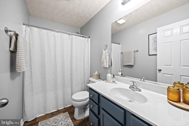 bathroom with toilet, vanity, wood finished floors, and a textured ceiling