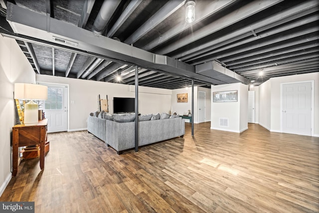 living room with wood finished floors, baseboards, and visible vents