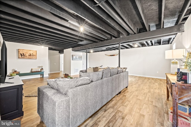living area featuring baseboards, light wood-type flooring, and visible vents