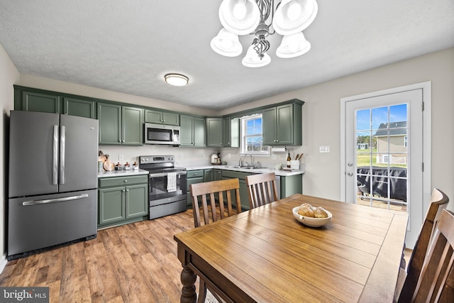 kitchen with light countertops, an inviting chandelier, a sink, green cabinetry, and appliances with stainless steel finishes