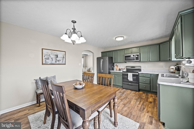 dining room with arched walkways, baseboards, a notable chandelier, and wood finished floors