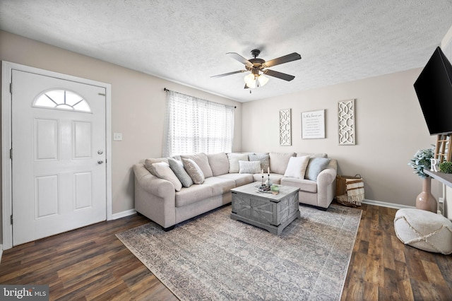 living area with a textured ceiling, dark wood-style flooring, baseboards, and a ceiling fan